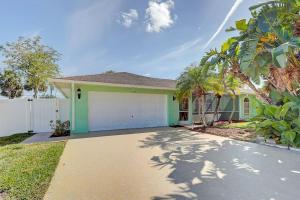 a green house with a garage and palm trees at Chateau Grove in Port Saint Lucie