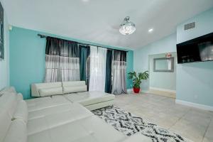 a living room with a white couch and a tv at Chateau Grove in Port Saint Lucie