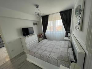 um pequeno quarto com uma cama e uma televisão em SunSet Apartament em Oradea