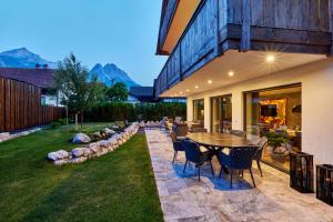 a patio with a table and chairs in a yard at Private Spa & Garden Alpi mit Sauna und Whirlpool in Garmisch-Partenkirchen