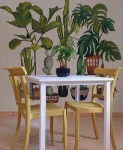 une table blanche et deux chaises avec des plantes sur le mur dans l'établissement MaNà Rooms and Apartment, à Telese