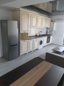 Una cocina con gabinetes blancos y un refrigerador. en Sun up Mamaia nord, en Năvodari