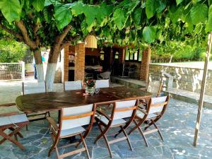 a wooden table and chairs under a tree at Villa ChrysPa Attica in Dhílesi