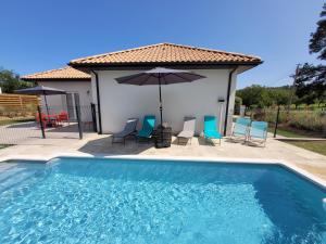 una piscina con sillas y sombrilla en Maison neuve bord de Dordogne en Lanzac