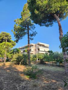 ein Gebäude inmitten eines Parks mit Bäumen in der Unterkunft Zouberi Τwins Luxury Appartments(South) in Nea Makri