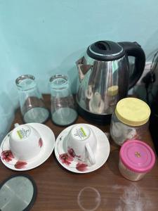 a table with two plates and a tea kettle at Teakwood Suite - Nokha House in Kolkata