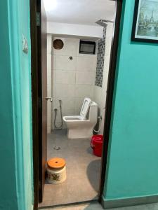 a bathroom with a toilet and a sink and a door at Teakwood Suite - Nokha House in Kolkata +13 photos