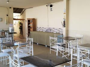 une salle avec des tables, des chaises blanches et un comptoir dans l'établissement POUSADA MONTE HOREB, à Cachoeira Paulista