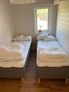 2 camas en una habitación con ventana en Lilla Sommarhuset Burgsvik, en Burgsvik