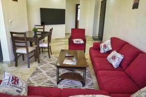 a living room with a red couch and a table at شقة فاخرة و واسعة من 4 غرف مع وسائل الراحة الحديثة Spacious 4-Room Apartment with Modern Amenities in Amman