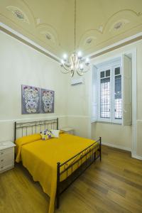 a bedroom with a yellow bed and a chandelier at Appartamento Martoglio - Casa Vacanze - in Catania