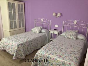 エルシエゴにあるCasa Rural La Corcheaの紫の壁のベッドルーム1室(ベッド2台付)