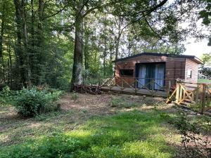 eine Hütte im Wald mit einem Zaun und Bäumen in der Unterkunft Le Chalet in Les Sorinières