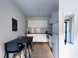 uma cozinha com armários brancos e uma mesa e cadeiras pretas em Casas S. Dinis no Porto