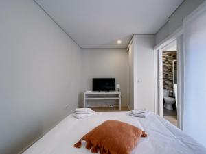 um quarto branco com uma cama e uma televisão em Casas S. Dinis no Porto