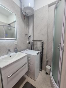 een witte badkamer met een wastafel en een douche bij Lady Di apartments in Kaštela