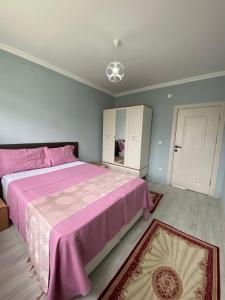 a bedroom with a large pink bed with a pink blanket at Şirin Villa in Macka