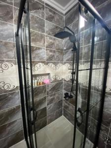 prysznic w łazience wyłożonej czarnymi kafelkami w obiekcie Şirin Villa w mieście Macka