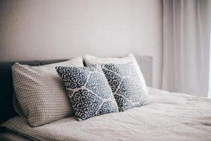 a bed with three pillows on top of it at Marinero Apartament in Puck