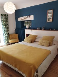 a bedroom with a large bed with a blue wall at PEGASUS in Blainville-sur-Orne