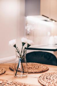 a glass vase with white flowers sitting on a table at Marinero Apartament in Puck