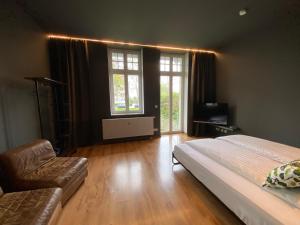 ein Schlafzimmer mit einem Bett, einem Sofa und Fenstern in der Unterkunft Tropisches Loft mit privatem Garten in Magdeburg