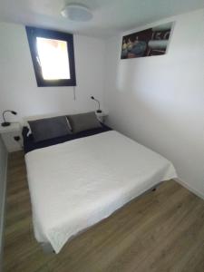 a white bed in a room with a window at Superbe bas de villa 80 m2 très calme et frais avec vue magnifique 6 couchages in La Londe-les-Maures