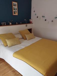 a bed with yellow and white sheets and pillows at PEGASUS in Blainville-sur-Orne