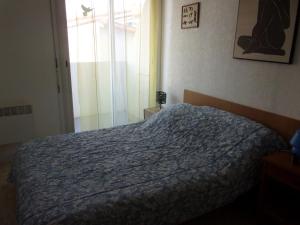 a bedroom with a bed with a blue comforter and a window at appartement saint hilaire de riez 85270 in Saint-Hilaire-de-Riez