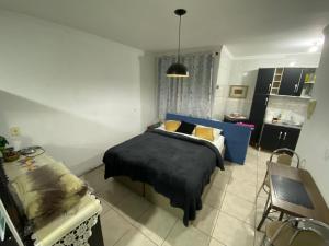 a bedroom with a blue bed and a kitchen at Estúdio central PG1 prox Paladium in Ponta Grossa
