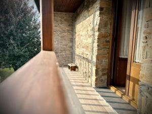 een veranda van een stenen gebouw met een houten deur bij La Casina de la Yeye San Cristóbal de Valdueza in San Cristóbal de Valdueza