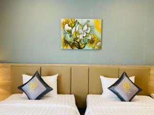 ホーチミン・シティにあるHera Luxury Hotelの壁に絵画が飾られた部屋のベッド2台