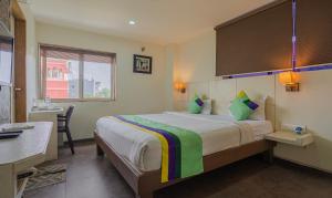 a bedroom with a large bed with a desk and a window at Hotel Casa, Vadodara in Vadodara