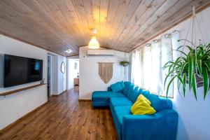 uma sala de estar com um sofá azul e uma televisão em הבקתה הכחולה - The blue cabin em Sha'al
