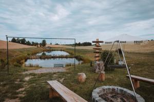 a pond in the middle of a field with a swing at Enklawa - Apartamenty z balią w otoczeniu natury in Nowy Podleś +39 photos