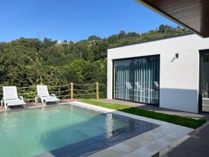 a swimming pool with two chairs next to a house at Casas da Veiga in Braga