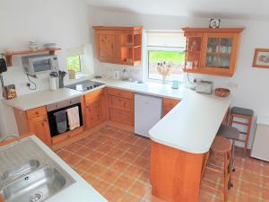 a kitchen with wooden cabinets and a white counter top at Cottage in Frogmore near Salcombe Estuary & Beaches in Kingsbridge