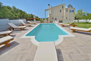 a swimming pool on a patio with benches around it at Dermitzogianni Villa in Kissamos
