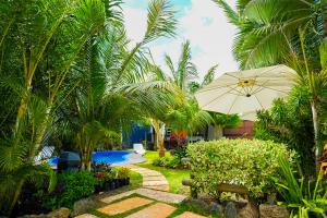a garden with a bench and an umbrella and a pool at Preety Blue Residence villas in Grand Baie