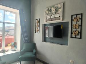 a living room with a tv and a chair and a window at Casa Chelito con Terraza in Guanajuato