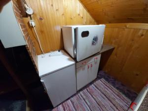 einen weißen Kühlschrank in einem Zimmer mit Holzwänden in der Unterkunft Julija Pansion in Senta