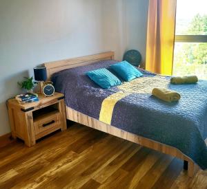 a bedroom with a bed with blue pillows and a table at Apartament Perełka in Jelenia Góra