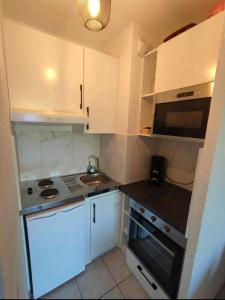 una pequeña cocina con armarios blancos y fregadero en 2 pièces proche plage + parking, en Golfe-Juan
