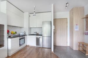 cocina con armarios blancos y nevera de acero inoxidable en Apartament Lema en Gdansk