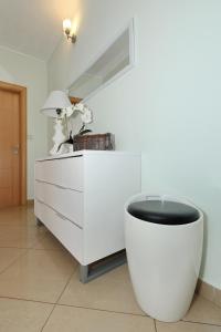 eine weiße Kommode mit einem Stuhl in einem Zimmer in der Unterkunft Sea Relaxing Apartment in Bibinje