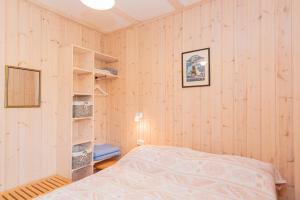 a bedroom with wooden walls and a bed and shelves at Vila RUNA in Plateliai