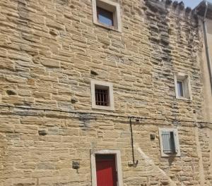 een bakstenen gebouw met een rode deur en ramen bij Petit appart au cœur des REMPARTS - Netfix et connection fibre gratuits in Carpentras