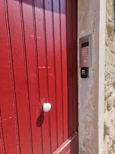 une porte rouge avec un bouton blanc sur un mur dans l'établissement Petit appart au cœur des REMPARTS - Netfix et connection fibre gratuits, à Carpentras