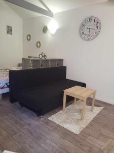 a living room with a black couch and a clock at Petite maison Juvisy, Orly 7 min, Paris 15min in Juvisy-sur-Orge +4 photos
