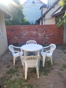 une table blanche et quatre chaises dans la cour dans l'établissement Petite maison Juvisy, Orly 7 min, Paris 15min, à Juvisy-sur-Orge